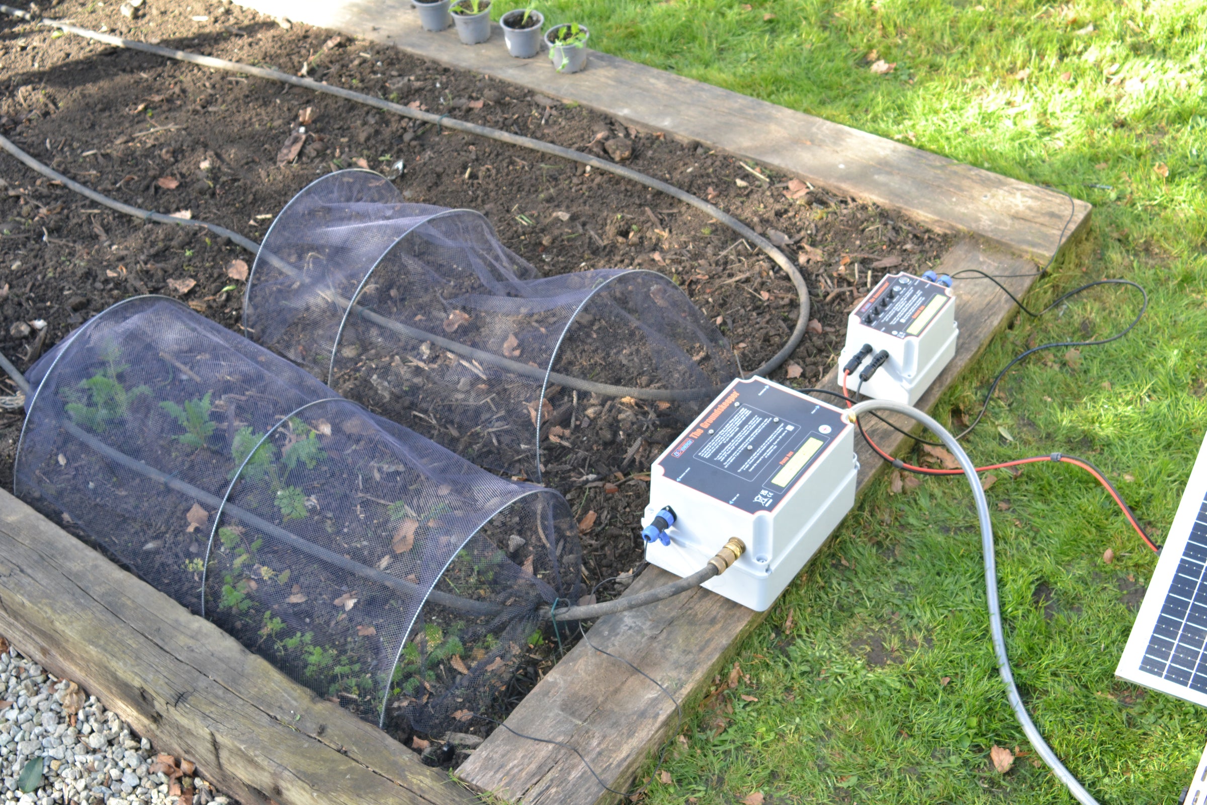 Groundskeeper solar-powered irrigation system with garden beds and plants.